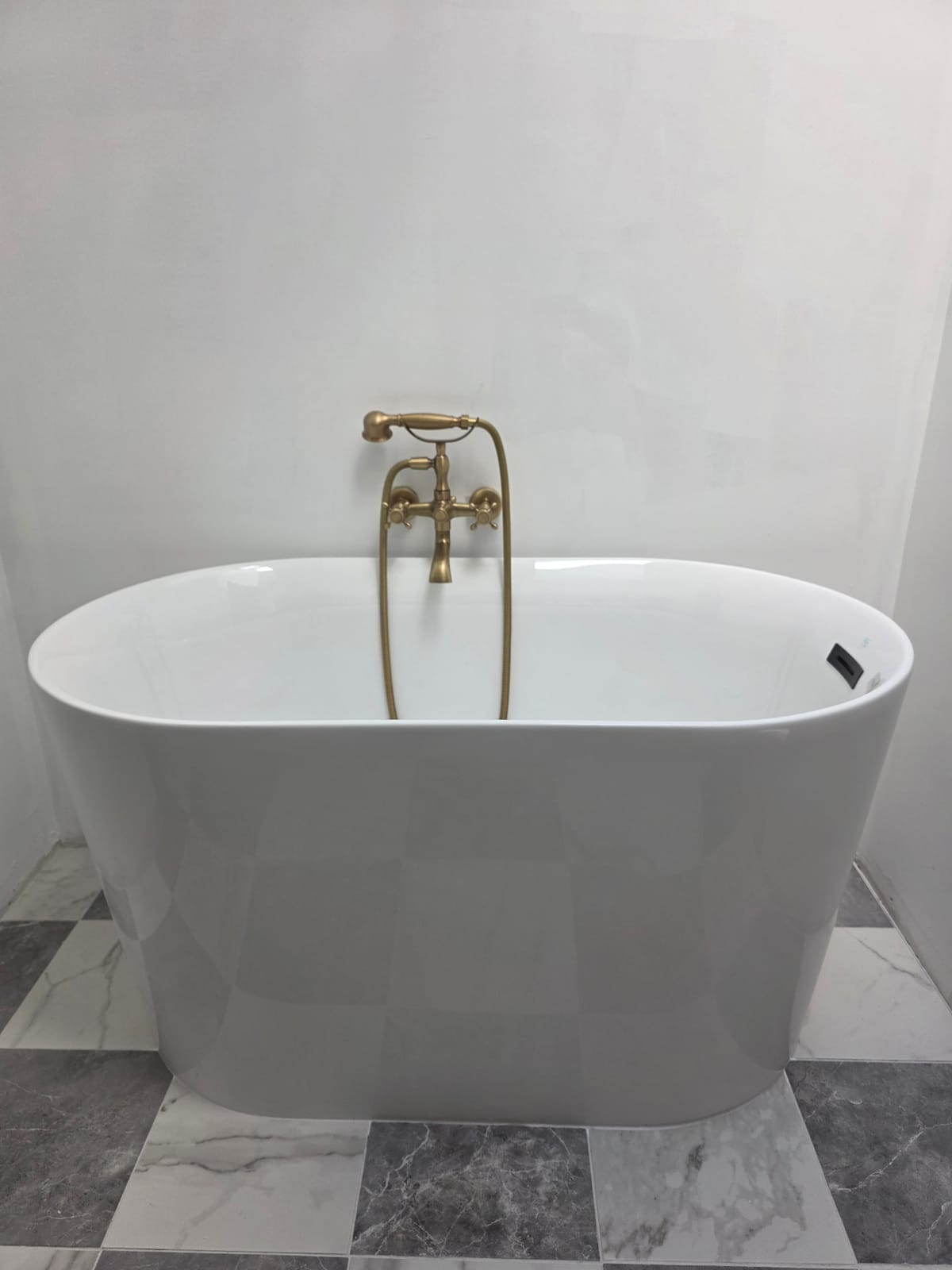 Finished freestanding soaker tub with brushed brass telephone-style filler installed by Panther Plumbing